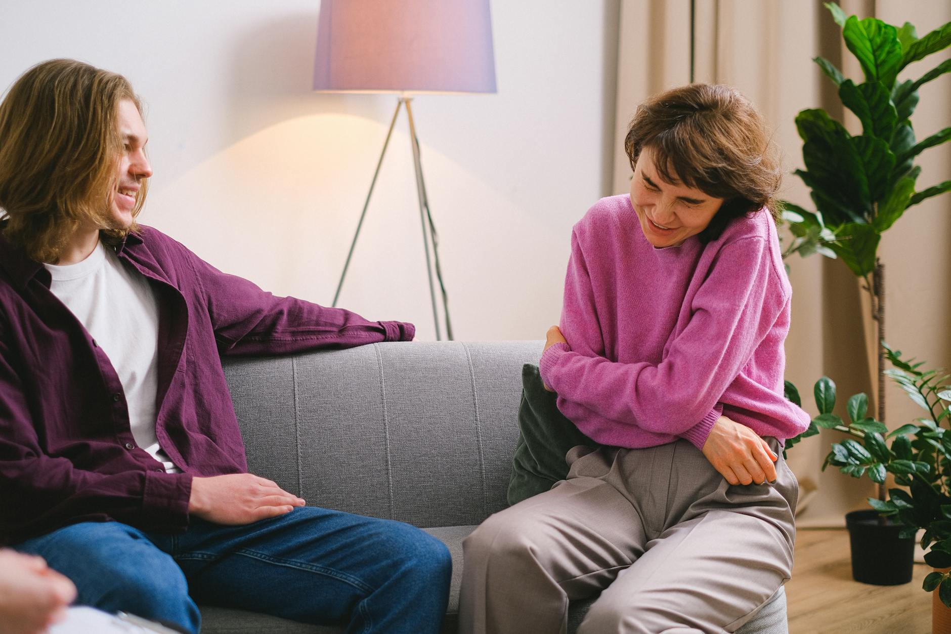 Dwie przyjaciółki śmieją się, siedząc razem na przytulnej sofie w salonie