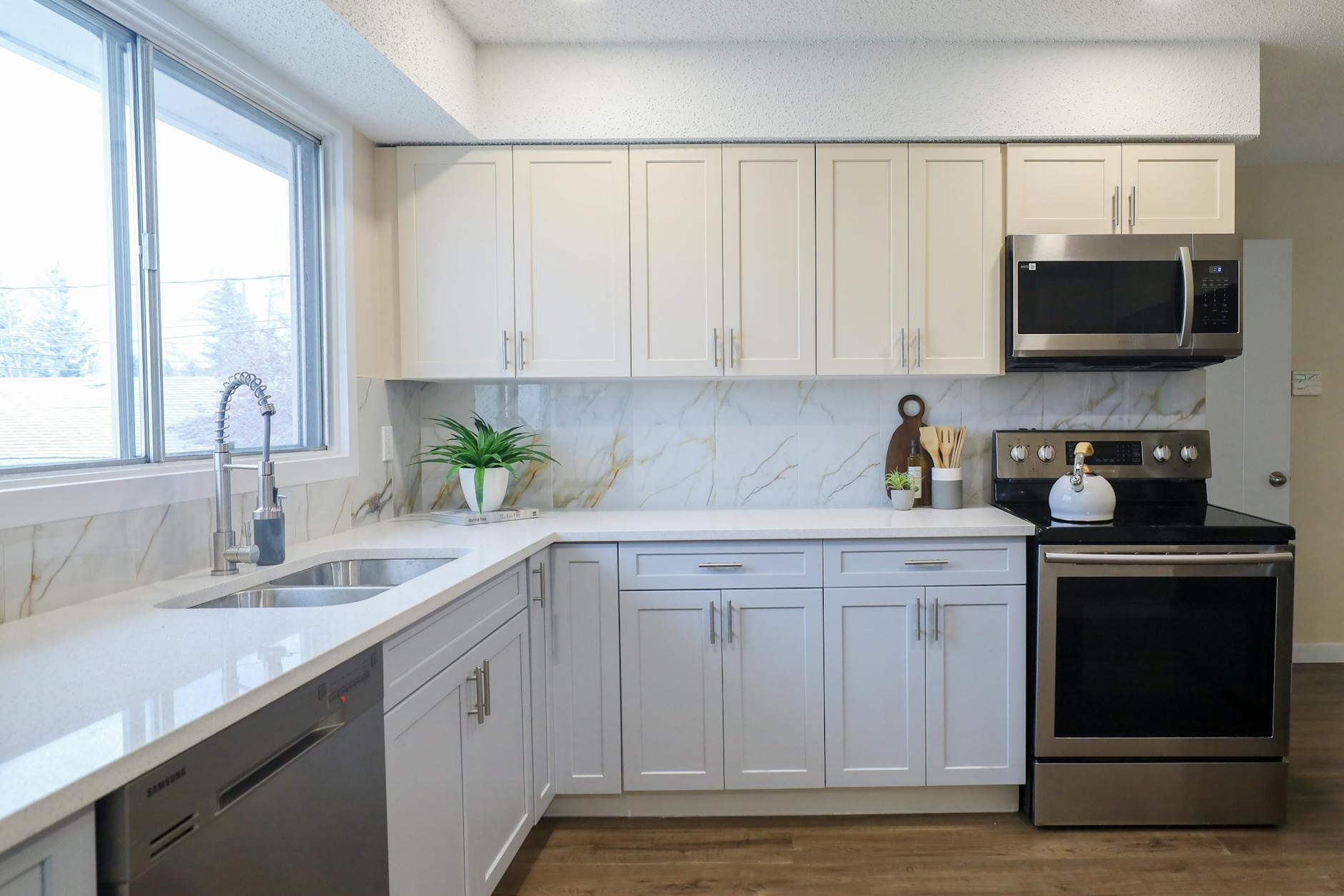 Nowoczesna jasna kuchnia w kształcie litery L ze stalowymi sprzętami