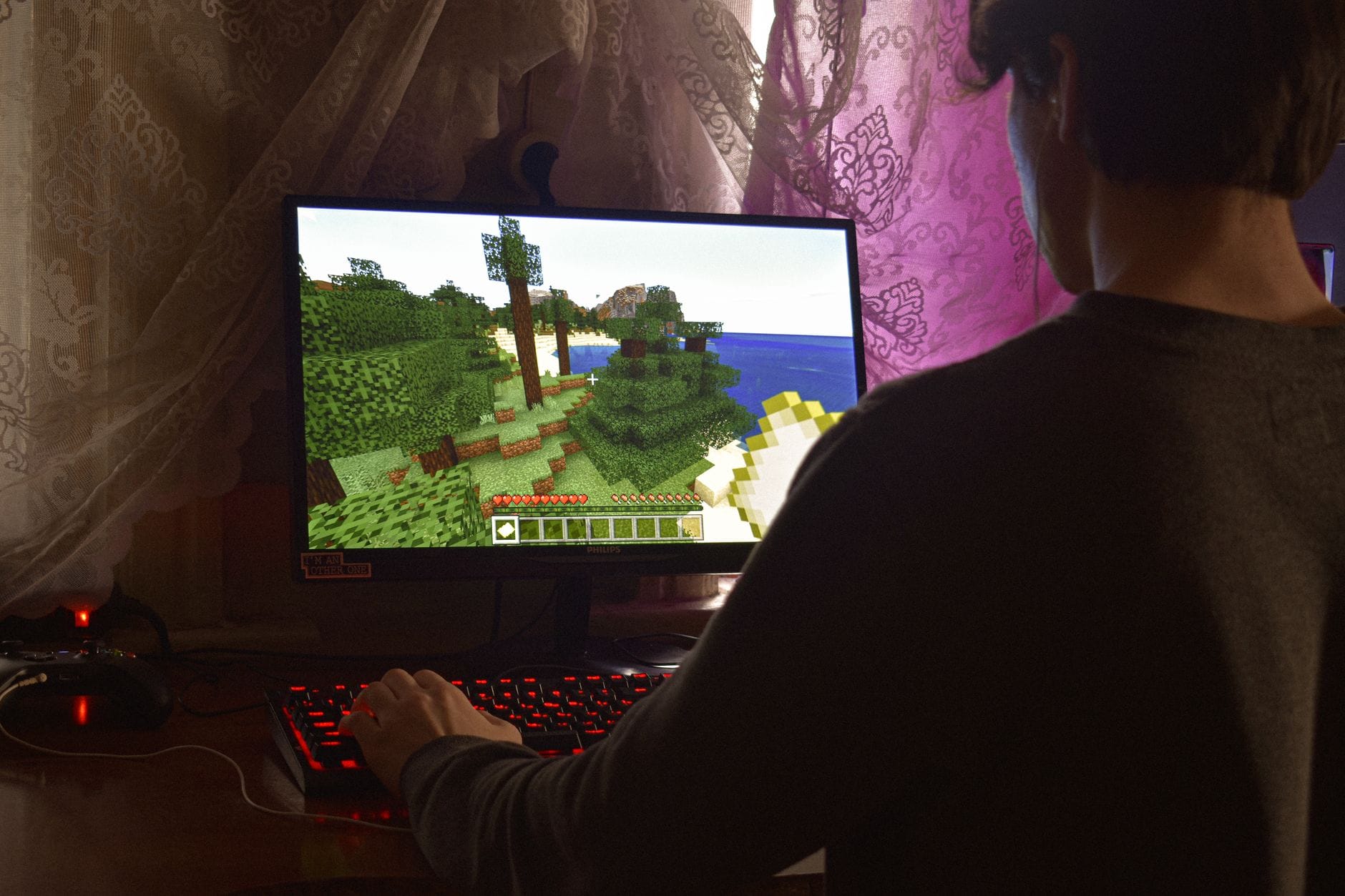 Młody mężczyzna skupiony na grze Minecraft przy komputerze