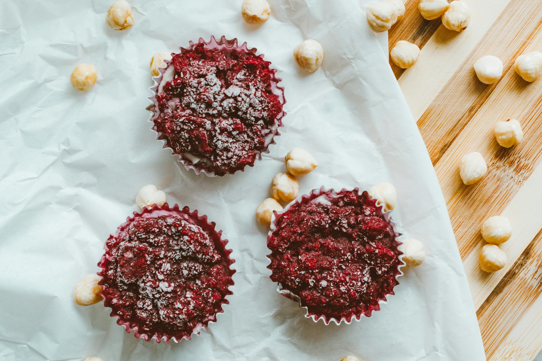 Trzy muffiny z jagodami i orzechami na papierze do pieczenia