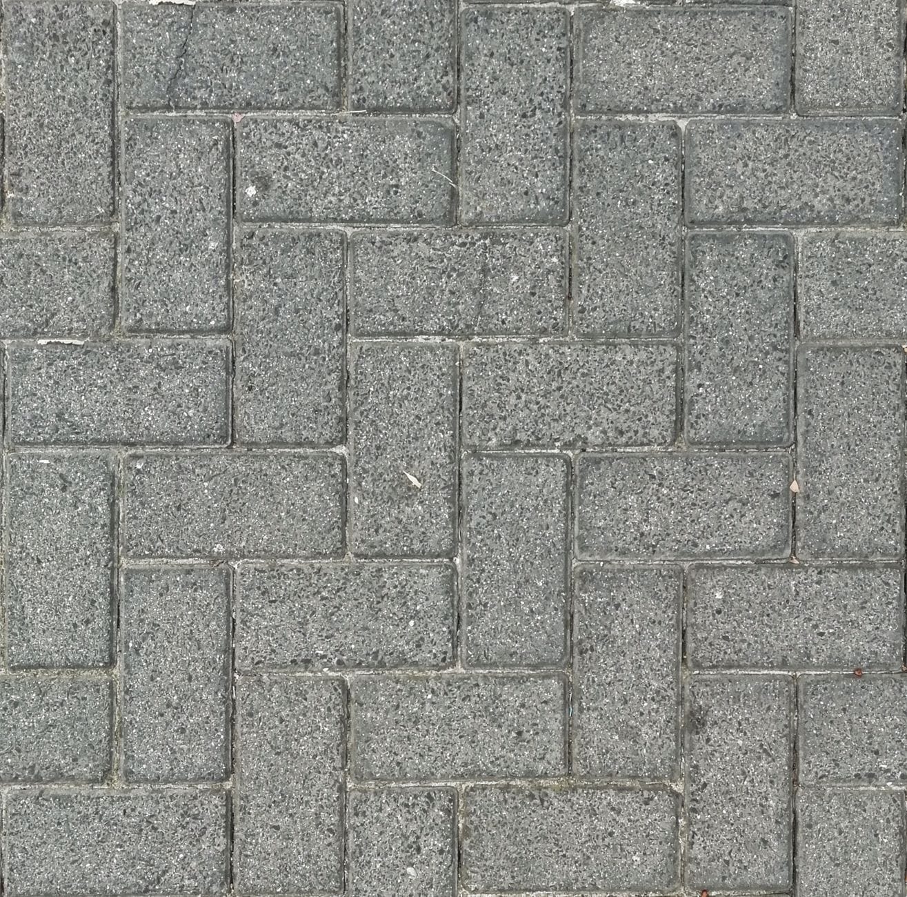 Podjazd z kostki betonowej dla ciężkich aut dostawczych, jakie grubości i warstwy zastosować, aby uniknąć pęknięć nawierzchni Szare kostki brukowe w jodełkę widziane z góry